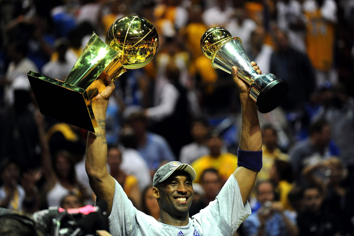 Kobe Bryant holding trophies. 